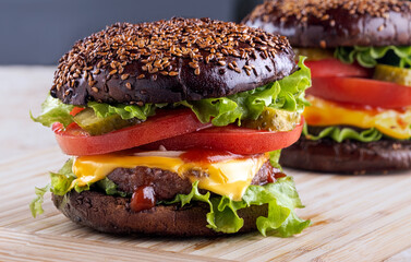 classic american homemade burger on the kitchen board. Bun with sesame seeds, pickled cucumbers, cheddar cheese, tomatoes, onions, meat cutlet.