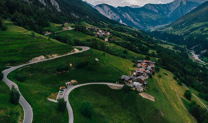 Fototapeta na wymiar Aerial view of picturesque valley in area of wild green Swiss hills. Bird's eye view of breathtaking countryside in mountains. Beautiful bicycle path spreads in hills of stunning nature landscape