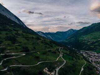 Aerial view of picturesque valley in area of wild green Swiss hills. Bird's eye view of breathtaking countryside in mountains. Beautiful bicycle path spreads in hills of stunning nature landscape