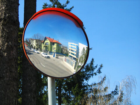 Round convex traffic mirror on the alley for better visibility. Convex mirrors provide a wider field of view on roads, driveways and in alleys. - Powered by Adobe