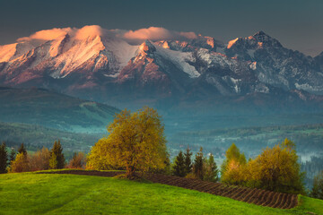 Fototapeta premium Spring in the Tatra Mountains. Green fields against the backdrop of snowy peaks. Landscape photo from Lesser Poland.