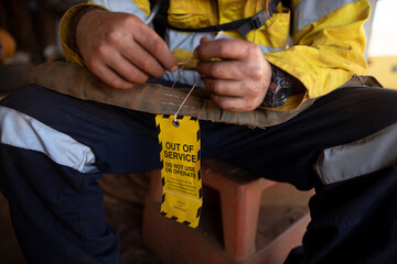Safety workplaces trained competent person inspecting and attached yellow out of service tag on...