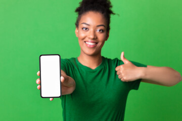 African girl showing white blank cell phone screen at studio