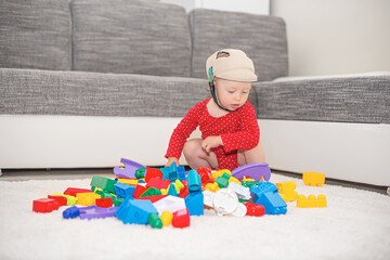 Child girl play in multi-colored toy blocks and cubes.