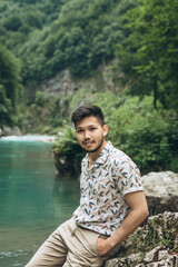 Portrait of a handsome positive young Kazakh man on a background of nature.
