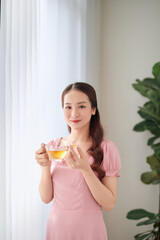 Young woman with glass of water taking vitamin pill at home