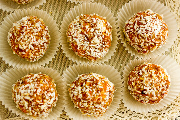 Healthy raw energy balls. Candy vegan balls of dates, coconut pulp, carrots in a wooden bowl are laid out in the shape of a pyramid. Top view, concept of useful home-made candies without sugar