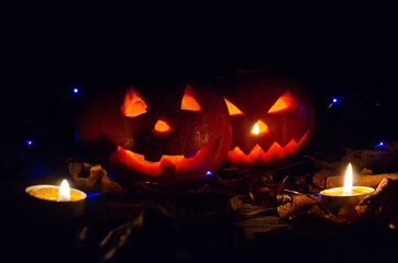 Two glowing pumpkins in the dark in the forest, candles lit around them. Beautiful background for Halloween.