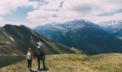 Fototapeta na wymiar Romantic couple of backpackers standing on mountain top and enjoying beauty of nature during vacations. Man and woman wanderlusts with rucksacks exploring scenery places traveling in National Parks