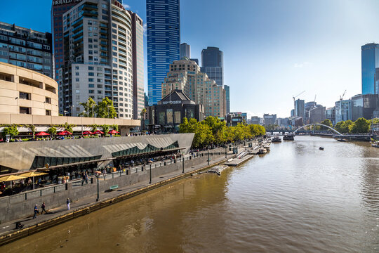 Melbourne, Australia - 05th March 2020: A german photographer visiting the Flinders Street, taking pictures of tourists walking along the river at a sunny day in summer.