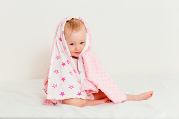 Baby covered in pink plaid sits