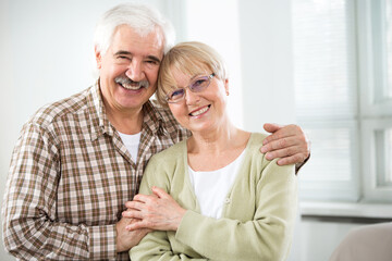 Happy elderly couple hugging at home and smiling
