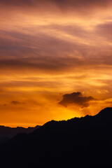 Sunset colours in sky over a mountain in silhouette