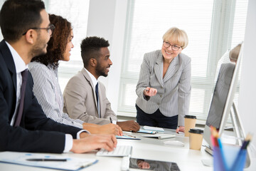 Mature businesswoman explains to young colleagues a new project
