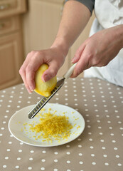 Closeup of woman rubbing lemon zest on grater