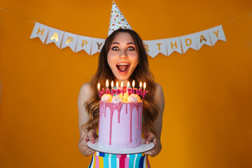 Image of delighted young woman showing birthday torte with candles