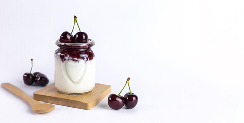 Dessert of natural yoghurt, jam and cherries on a white background. Healthy breakfast. Banner