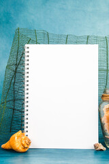 Jar full of seashells with the starfish and blank paper page on a blue background