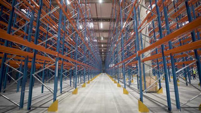 Warehouse, storage racks and shelves industrial logistic delivery. Large logistics warehouse. Shooting between metal shelves in a huge logistics center.