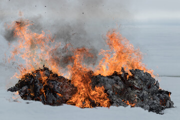 Fire and smoke from burning trash on a snow covered field