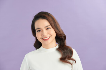 Fototapeta premium Beautiful young woman smiling against purple background.