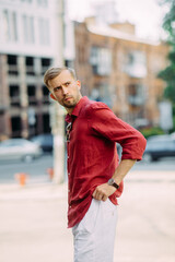 Young man stands on street near building.