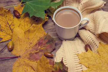 Autumn mood. White cup of coffee and yellow maple leaves, yellow scarf. top view