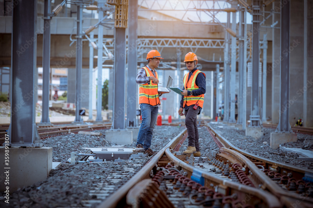 Wall mural Engineer under discussion inspection and checking construction process railway switch and checking work on railroad station .Engineer wearing safety uniform and safety helmet in work.