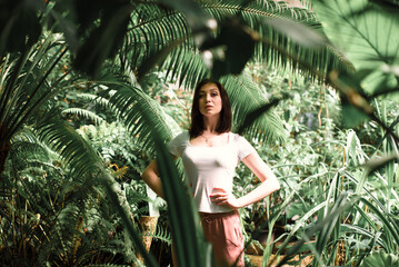 A beautiful young girl walks through an old greenhouse. Woman in the Botanical garden
