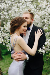 young beautiful couple in the garden against the background of cherry blossoms