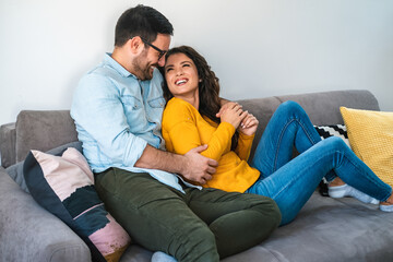 Obraz premium Couple is hugging and smiling while sitting together on couch at home stock photo