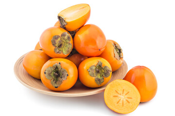 Pile of fresh raw persimmon fruit on wooden plate, isolated on white background, one cutted in half