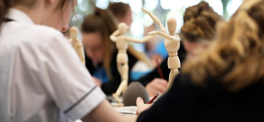 Visual Art high school students working from wooden mannequins practicing drawing human fugure and...