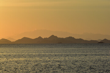 Naklejka na ściany i meble Sunset over the sea with mountains silhouette, Komodo Island, Labuan Bajo, East Nusa Tenggara, Indonesia