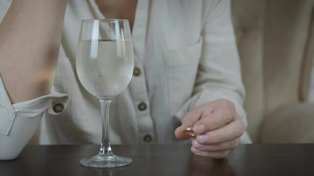 Marriage ring in alcohol. A woman throws her wedding ring into a glass of wine.