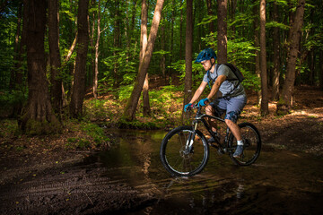 Fototapeta na wymiar Guy riding on a bicycle in a puddle in the woods