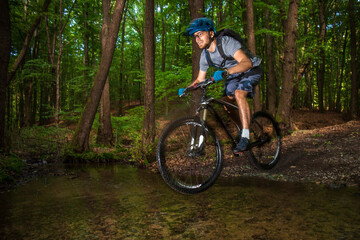 Mountain biker jumping in a puddle in forrest