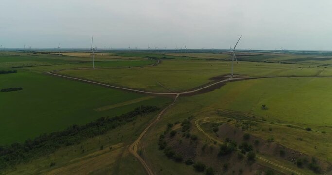 Natural panorama. Towers of wind farms in a field among green grass. Environmentally friendly source of energy and electricity. Aerial shot