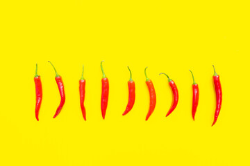 Flat lay red chili peppers pattern on yellow background. Top view