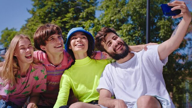 Good looking group of friends with a perfect large smile multiethnic have a fun time in the park they take some selfies in front of the camera using modern smartphone. Shot on ARRI Alexa Mini