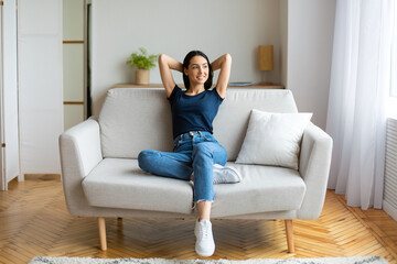 Obraz premium Girl Resting Holding Hands Behind Head Sitting On Sofa Indoors