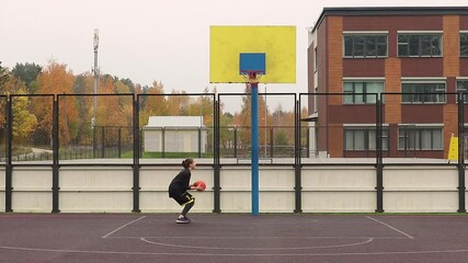 footage of a young girl basketball player training and exercising outdoors on the local court.  Sporty Teenager girl doing sport