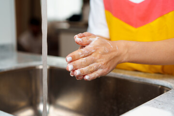 Close up of a woman washing her hands in a kitchen sink