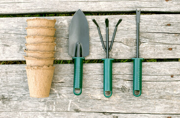 Garden tools and peat cups for seedlings on a wooden background. A concept image of garden...