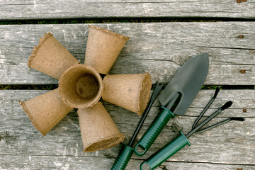 Garden tools and peat cups for seedlings on a wooden background. Concept image of garden equipment.