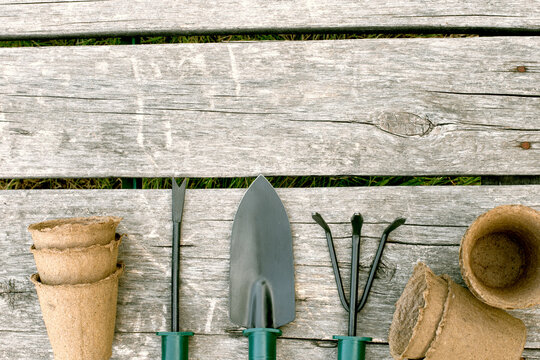 Garden tools and peat cups for seedlings on a wooden background. A concept image of garden equipment with a copy space.
