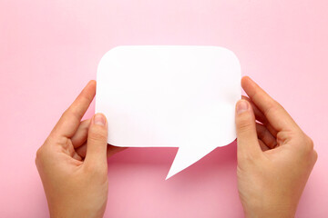 Obraz premium Hand holding an white empty speech bubble on pink background