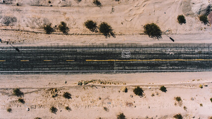 Top view of asphalt roadside crossing desert environment in USA, aerial scenery view of famous interstate landmark of Historic Route 66 located in wild lands