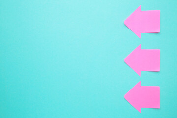 Pink paper sticky notes in shape of arrow on blue background - obrazy, fototapety, plakaty