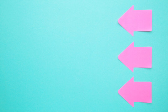 Pink paper sticky notes in shape of arrow on blue background